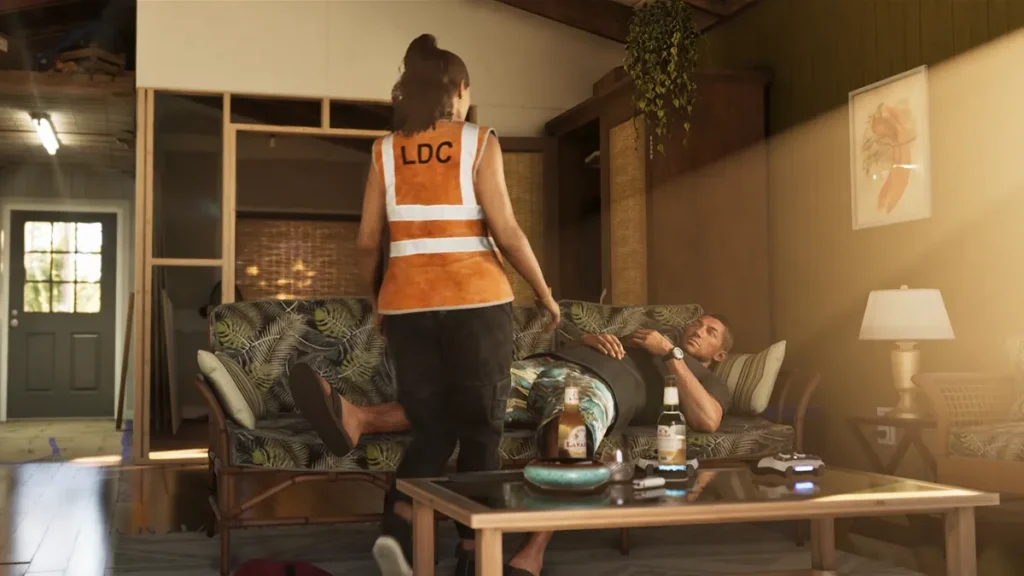 Lucia in an orange LDC vest stands in front of Jason, who is lying on a tropical-patterned couch with beer bottles and a game controller on the coffee table