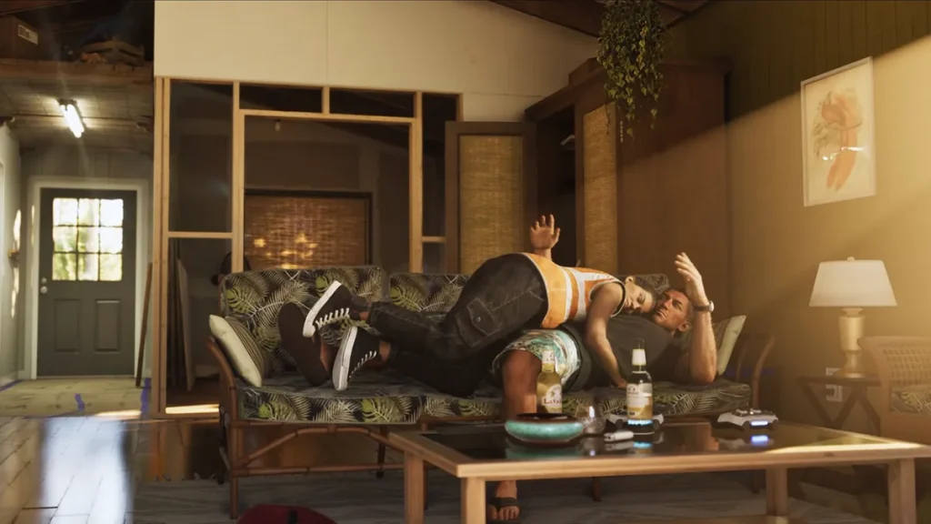 Lucia in an orange LDC vest straddles Jason on a couch during a tense moment, with beer bottles and a game controller on the coffee table nearby